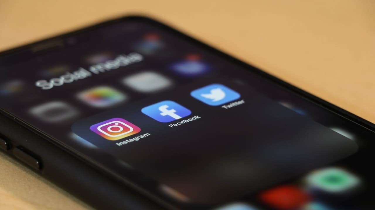 A smartphone displaying a social media feed held in one hand