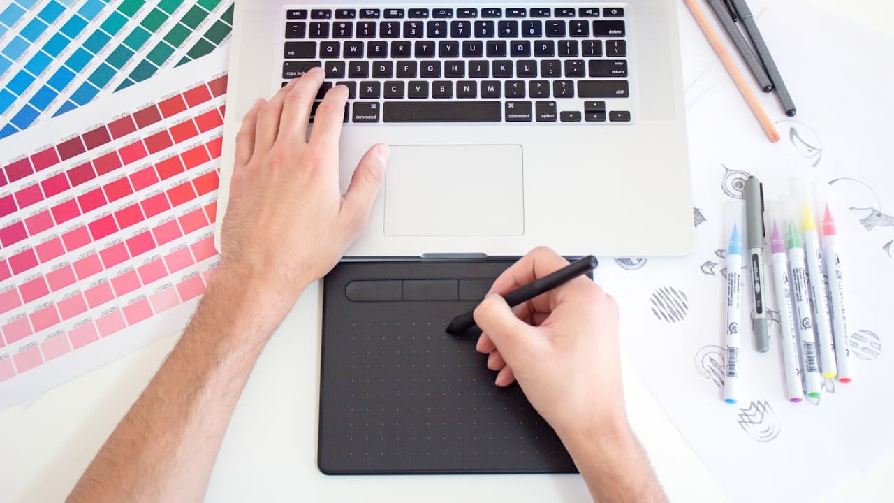 A designer working on an illustration with a graphics tablet and colour swatches
