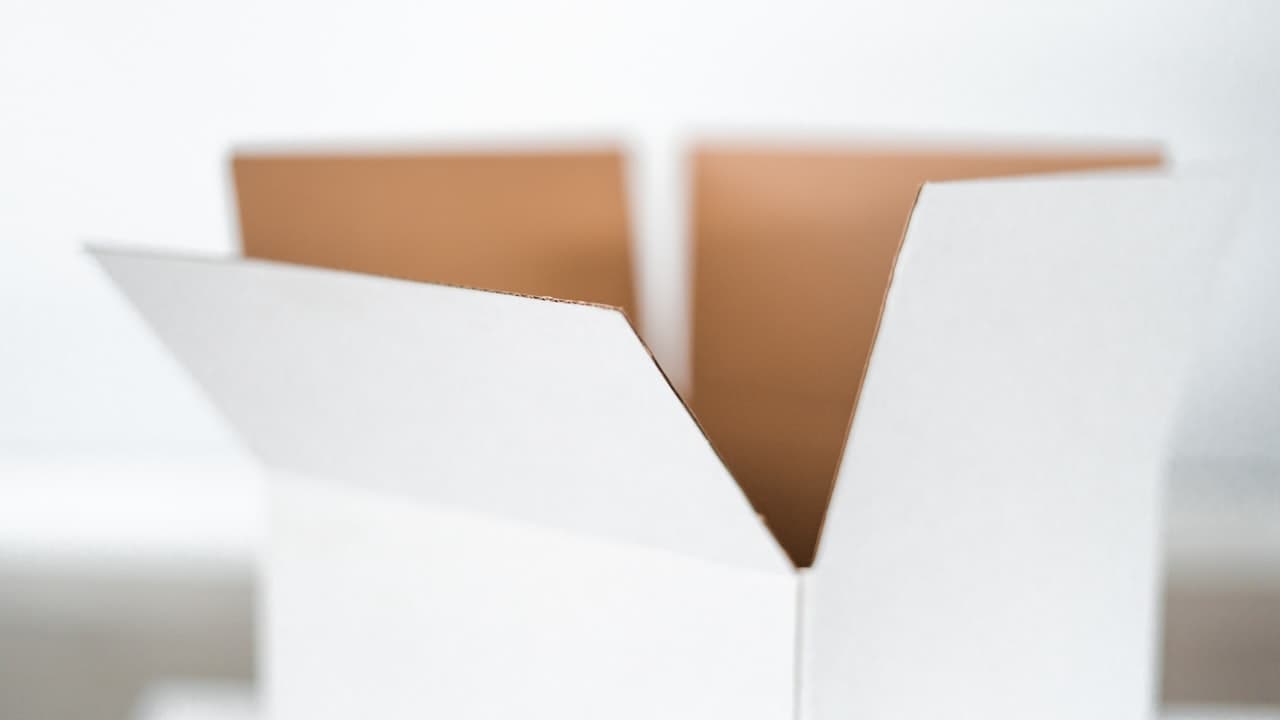 Close-up of hands opening a plain white product box