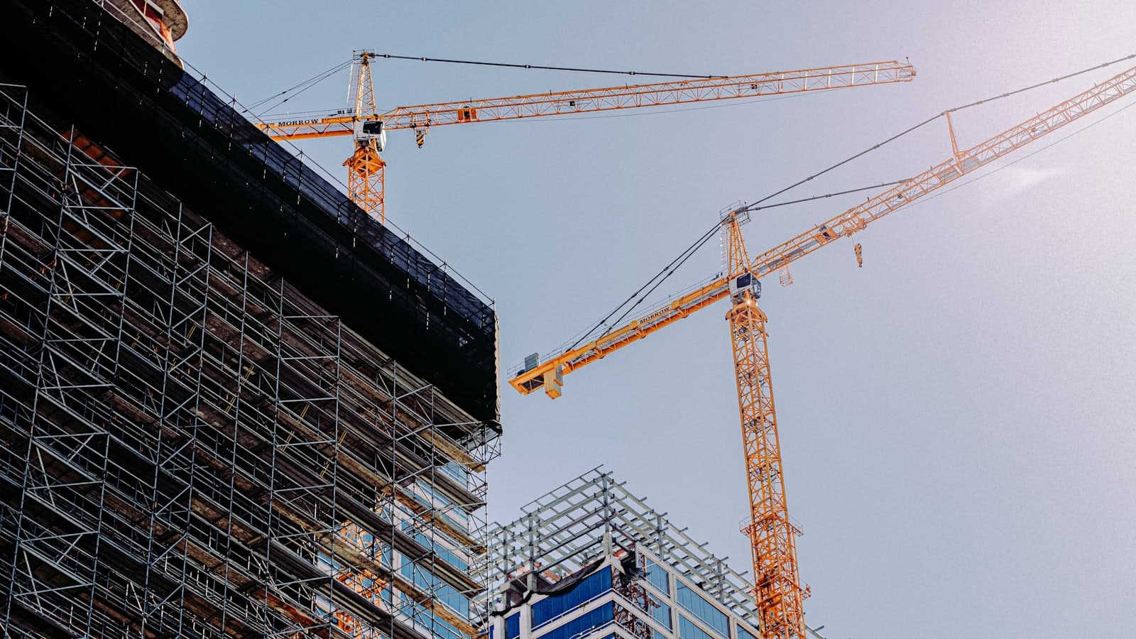A yellow tower crane beside a building under construction