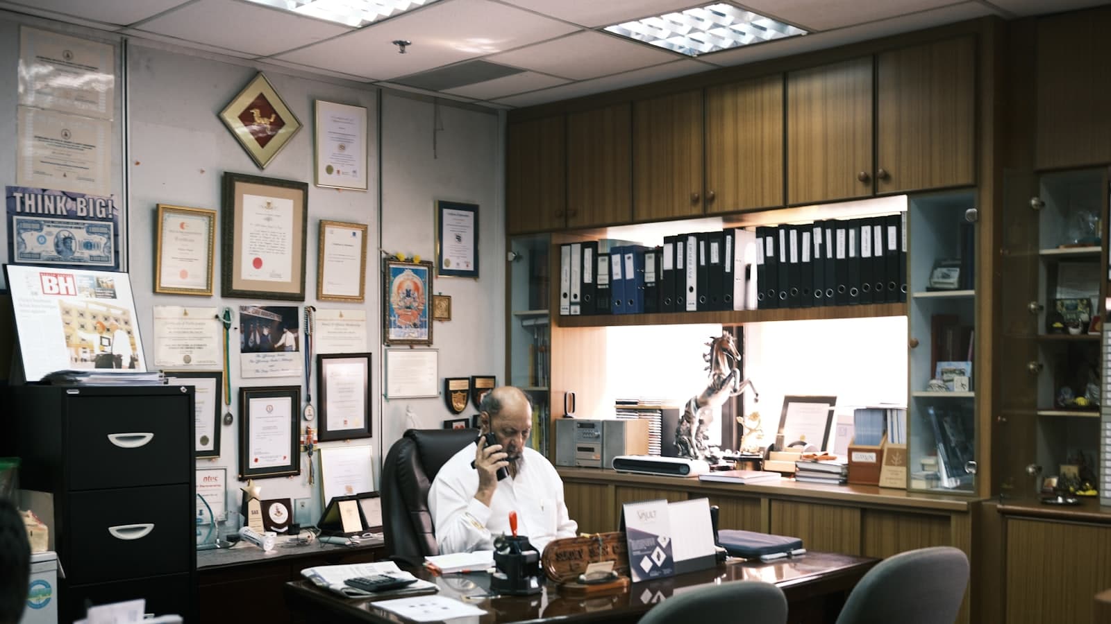 A person seated at a desk in an office during a filmed interview