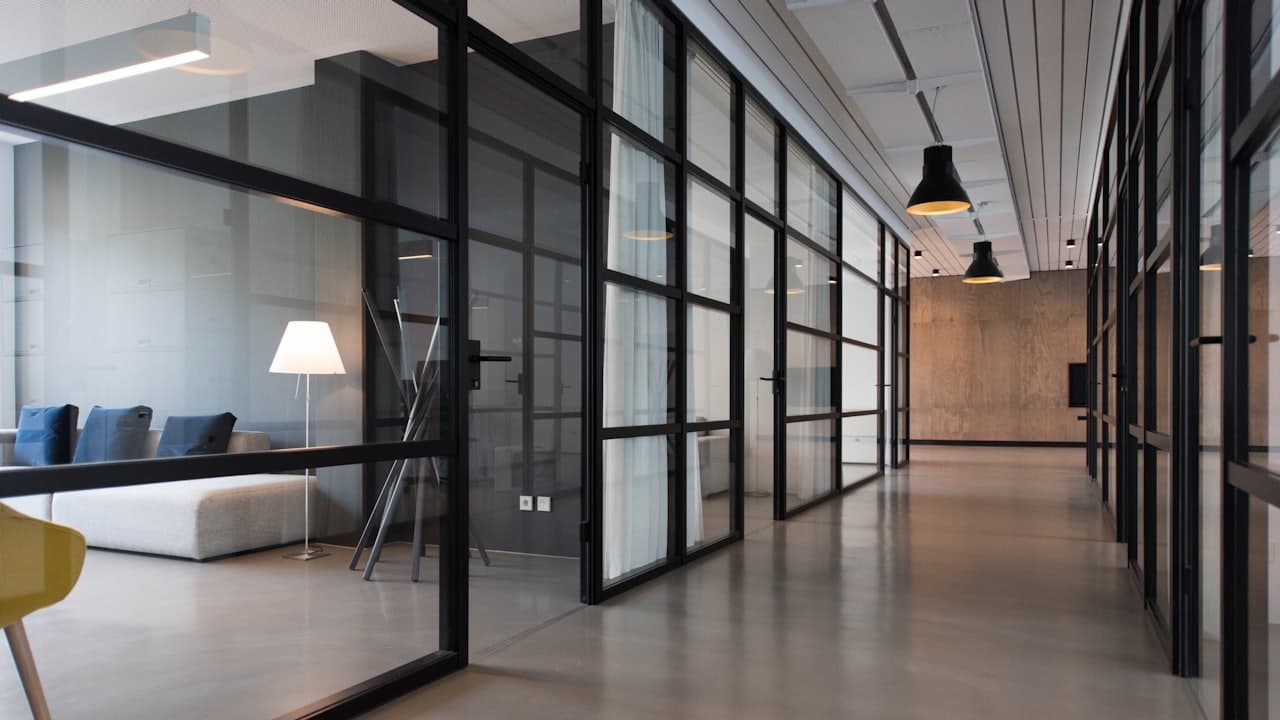 A modern office interior with glass partitions and a long hallway