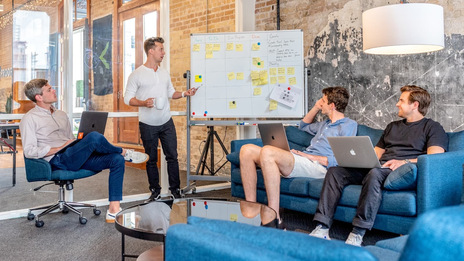 A team working through a project plan around a whiteboard in a meeting room