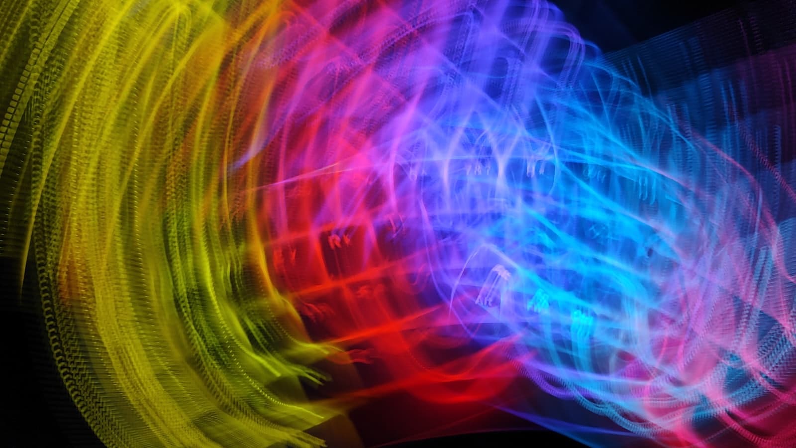 Abstract coloured light trails forming a wave pattern against darkness