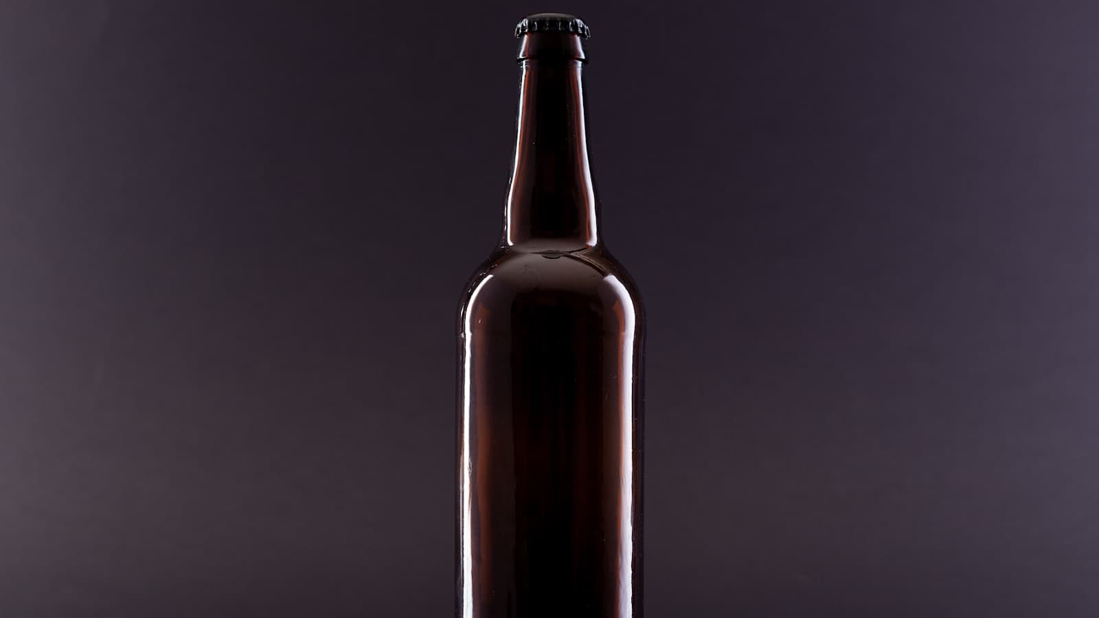 A brown glass product bottle lit against a black studio background