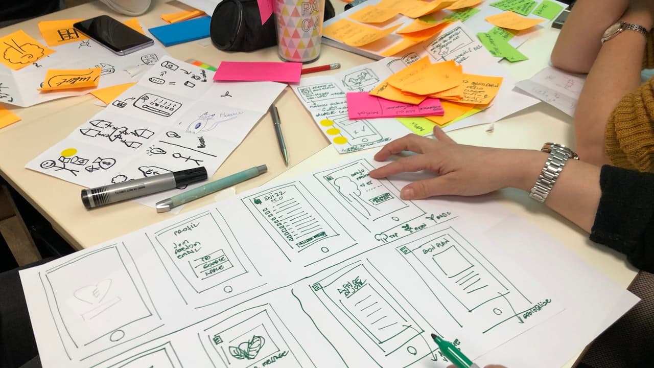 A person sketching app wireframe screens on paper