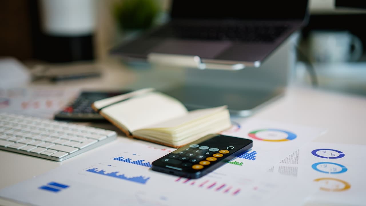 A desk with a phone and printed financial charts, mid-budget-review